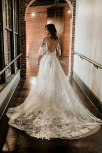 bride posing to show back of wedding dress in hallway