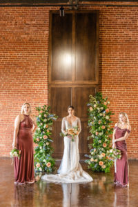 bride standing between bridesmaids and flower pillars