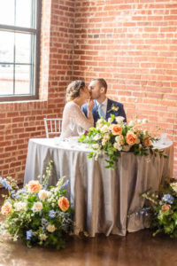 bride and groom kissing at sweetheart table