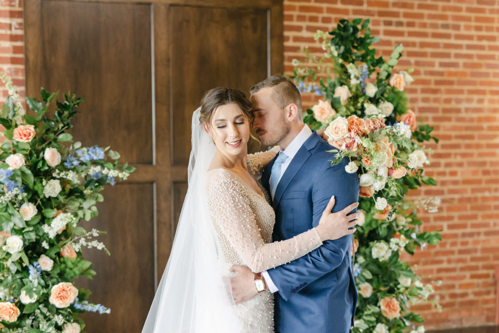 bride and groom posing between flower pillars