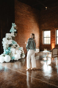 bride in white jumpsuit posing with bedazzled bride jean jacket