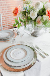 reception table with clean silverware and white and orange flowers
