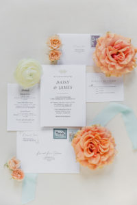 wedding invitations between orange and white flowers