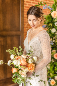 bride holding bouquet of white and orange flowers
