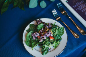 fresh salad on white and gold plate by gold silverware