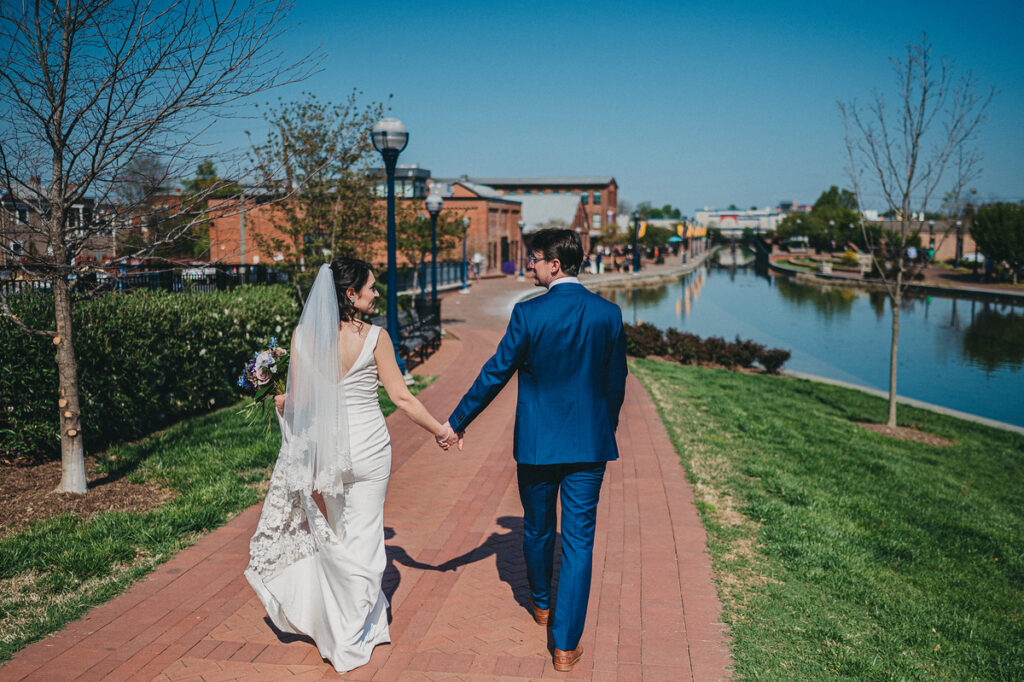 bride and groom holding hands walking along carroll creek