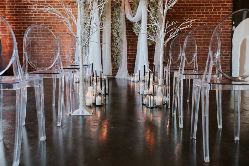 beautifully decorated wedding aisle with candles and clear chairs