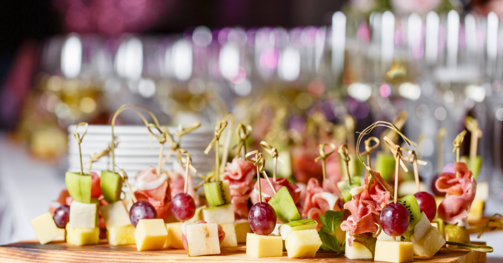 caterer appetizers with cheese and fruit on wood board