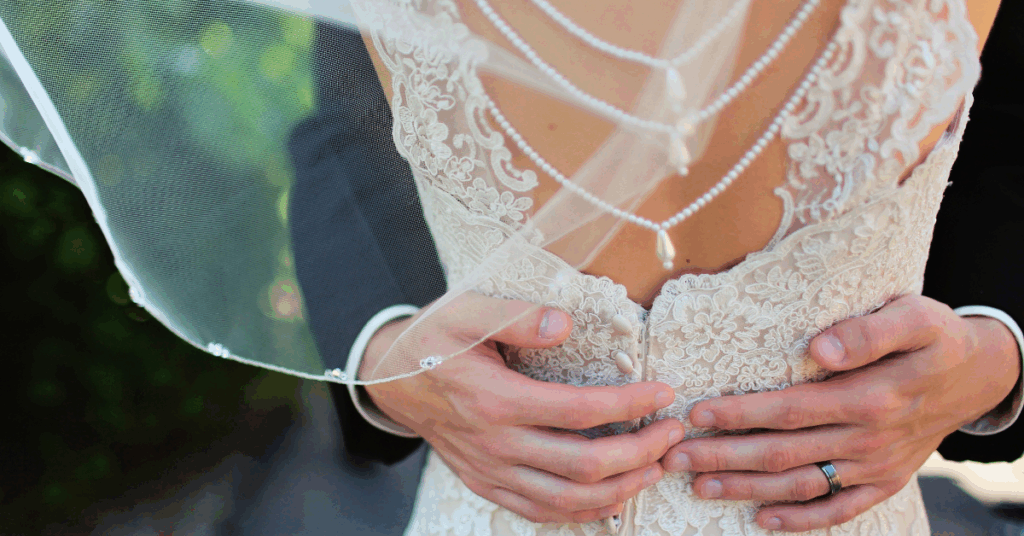 Groom's hands resting on the back of his new wife